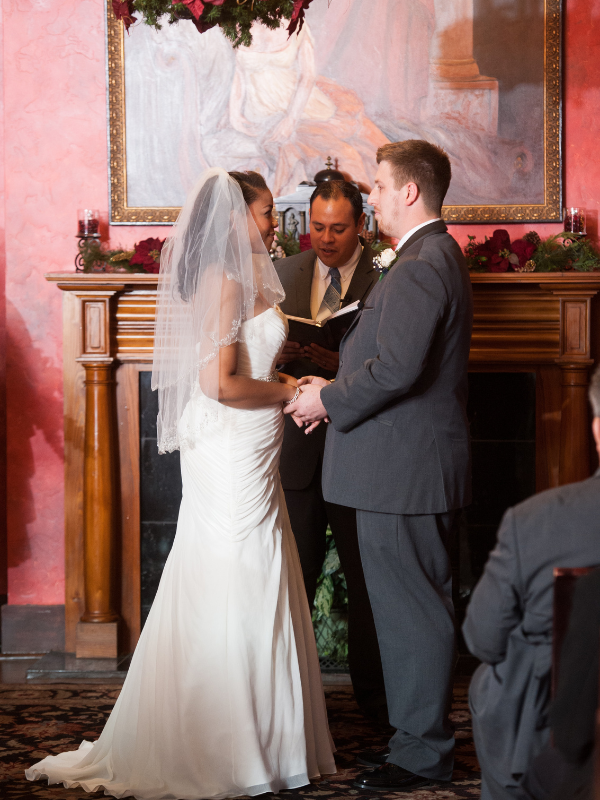 Everlasting Elopements couple standing in front of fireplace holding hands during their ceremony at Pat O'Brien's Briar Suite