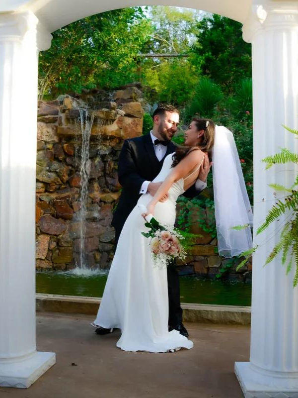 Everlasting Elopements couple smiling and the bride is holding up their marriage license in front of a door at Chapel Dulcinea 